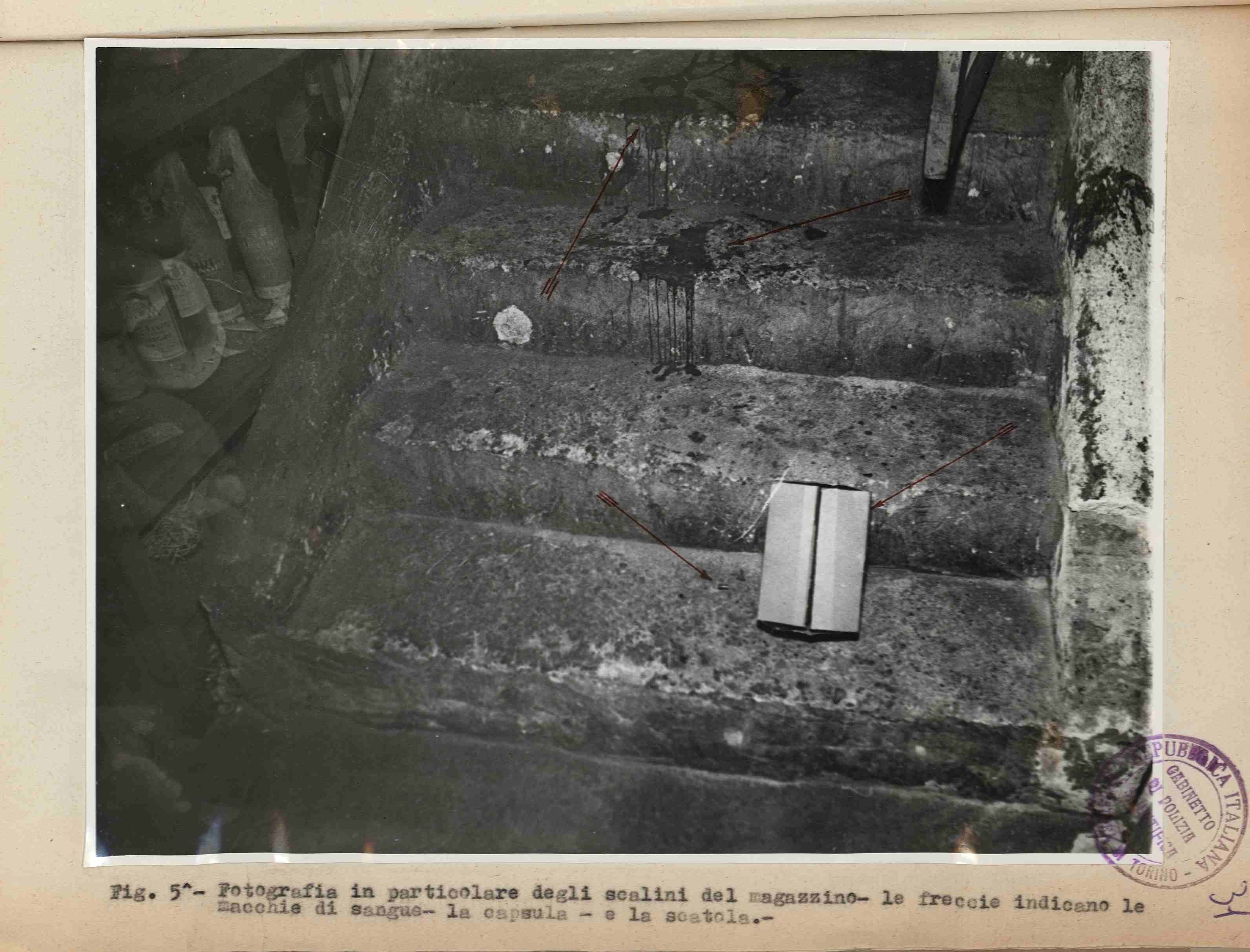 Dettaglio delle scale del bar che portano al magazzino, con le macchie di sangue e la cartuccia del proiettile